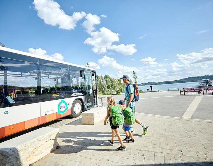 VGN Freizeitlinie Auf dem Bild ist ein Bus der Seenlandlinie an der Freizeitanlage am Brombachsee zu sehen. Ein Vater mit 2 Kindern will gerade in den Bus steigen.